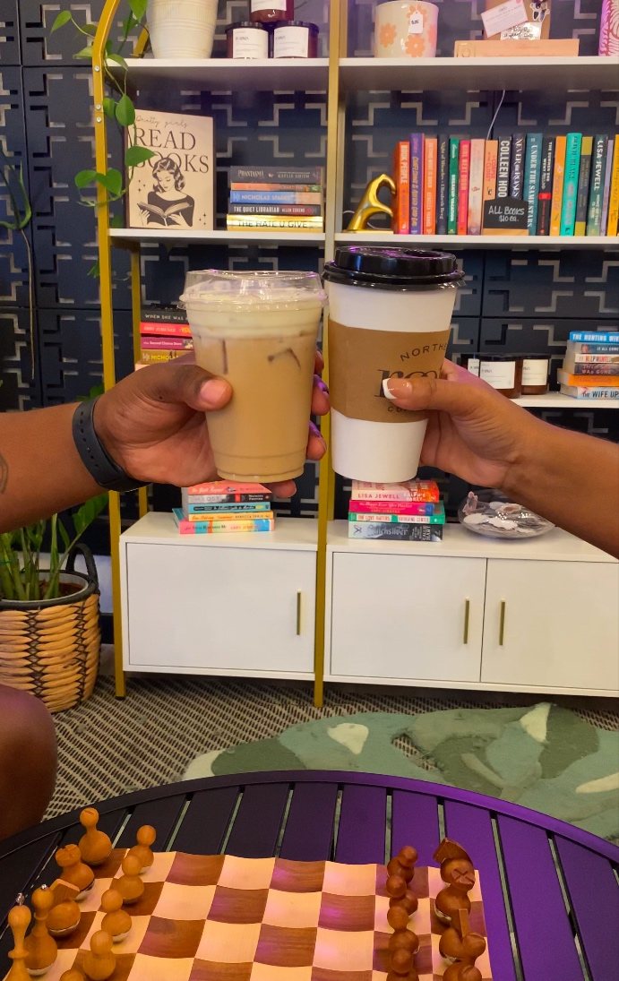 Two hands raising coffee cups together across a table