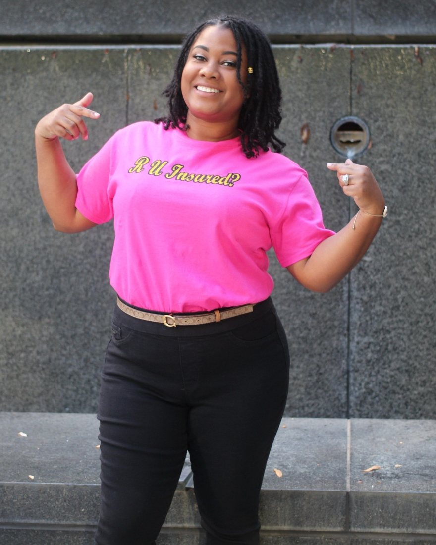 Fallon Simmons smiling and pointing at her T-shirt, which reads &lsquo;R U Insured?&rsquo;